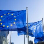 Des drapeaux européens devant le Conseil européen qui adopte certaines directives