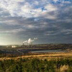 paysage de forêt avec une usine à l'horizon dégageant de la fumée