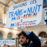 Un manifestant avec une pancarte à la main appelant à sauver les trains de nuit.